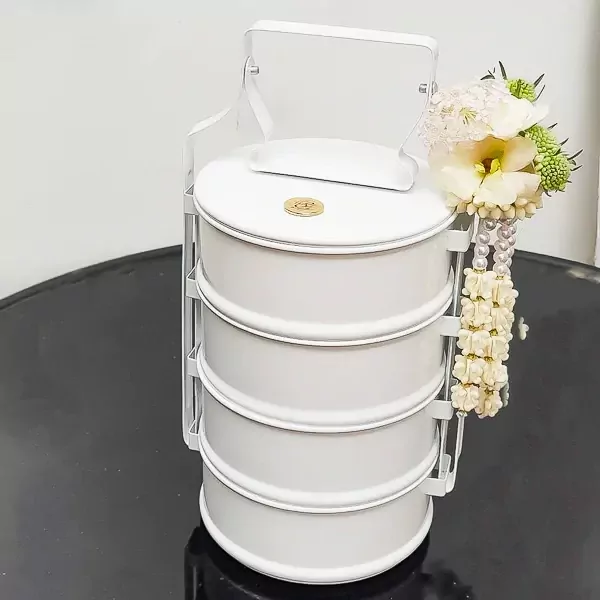 White stacked food carrier with flower garland and gold coin detail.