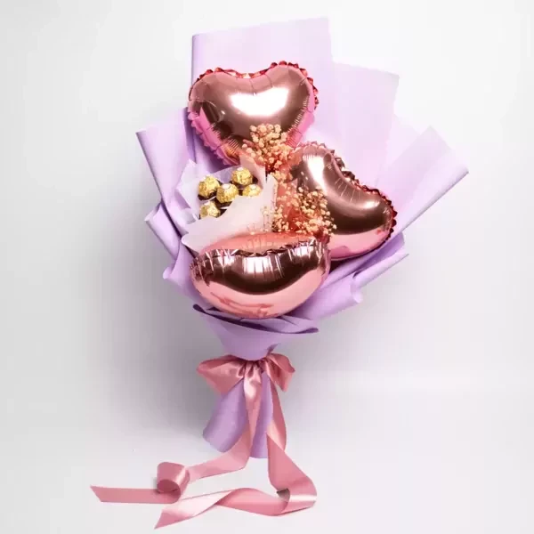 Pink heart balloons and Ferrero Rocher chocolates in a lavender bouquet with pink ribbon.