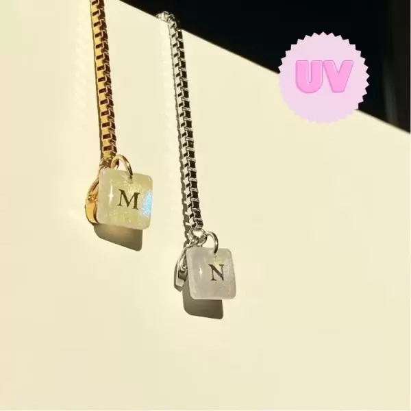 Gold and silver bracelets with UV color-changing square charms with letters M and N.