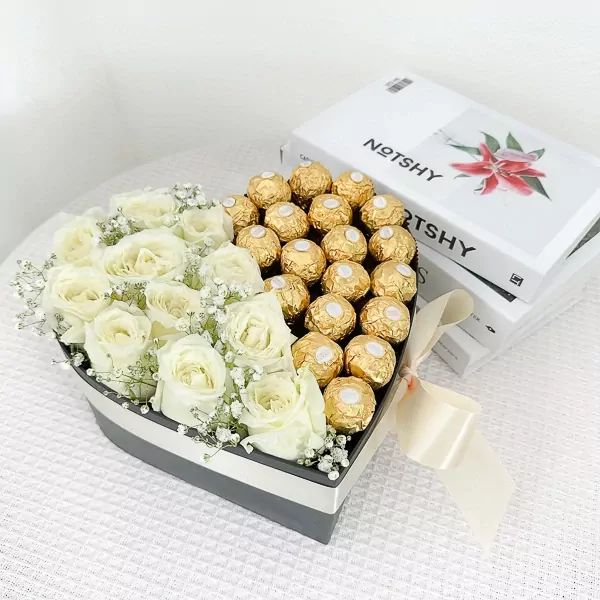 Heart-shaped box with white roses and Ferrero Rocher chocolates, tied with a ribbon.