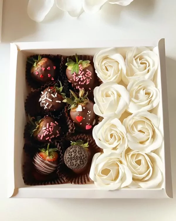 Chocolate-covered strawberries and ivory roses in a white gift box.