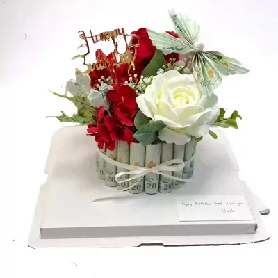 Money cake with red and white roses, money rolls forming the base, and a butterfly made of money.
