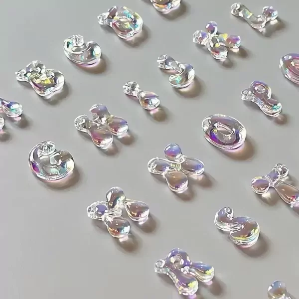 Iridescent acrylic letter charms arranged on a gray surface.