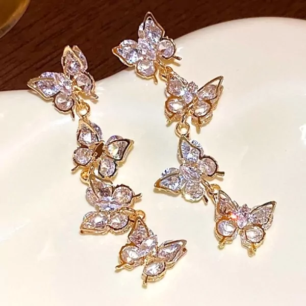 Dangle earrings with gold-tone metal, featuring multiple clear, sparkling zircon-encrusted butterfly charms.
