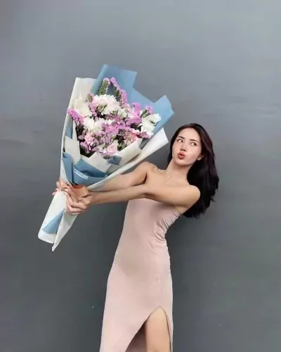 Woman in a pink dress holding a large bouquet of pink and white flowers.