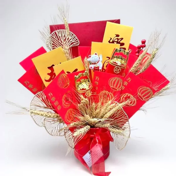 Red and gold Lunar New Year gift arrangement with red envelopes, wheat stalks, and a lucky cat.