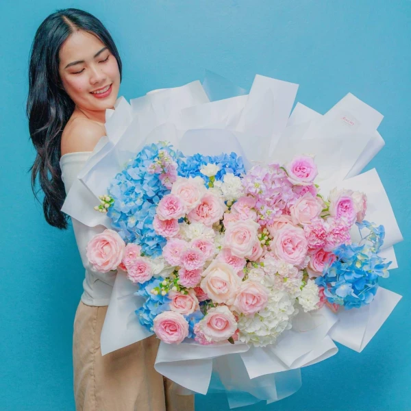 An grand fresh bouquet featuring a dreamy blend of serene blue hydrangeas and pastel pink roses.