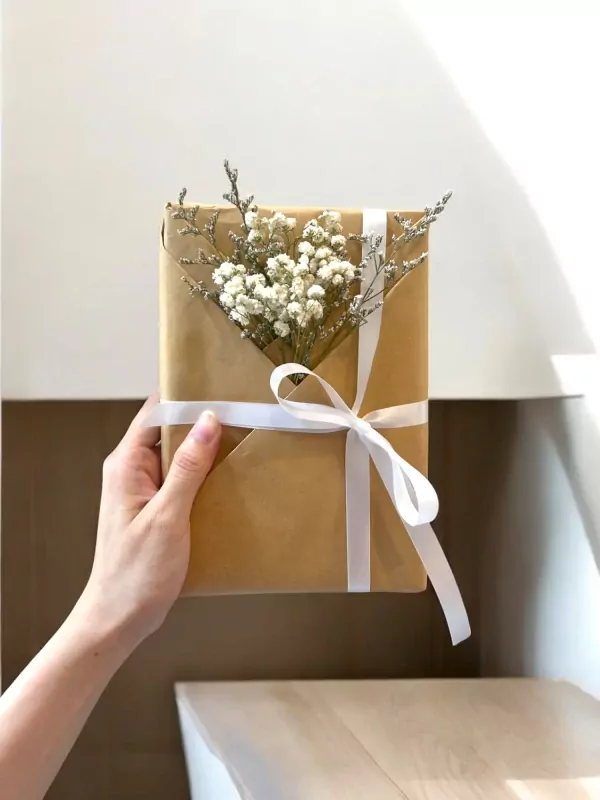 A gift-wrapped book with dried flowers and a white ribbon.