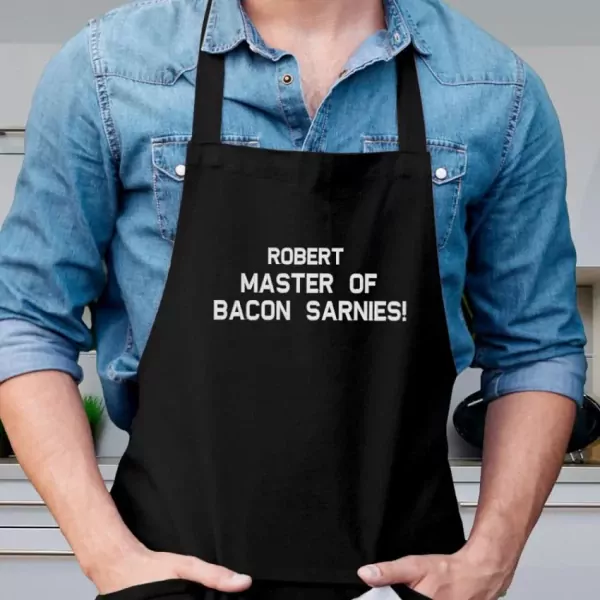 Black apron with "ROBERT MASTER OF BACON SARNIES!" printed in white text.