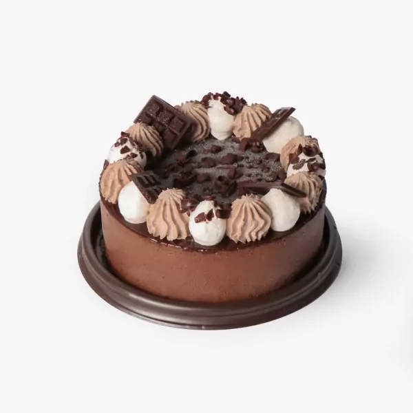Decadent chocolate cake with chocolate ganache frosting, piped whipped cream, chocolate chunks, and chocolate bar pieces.