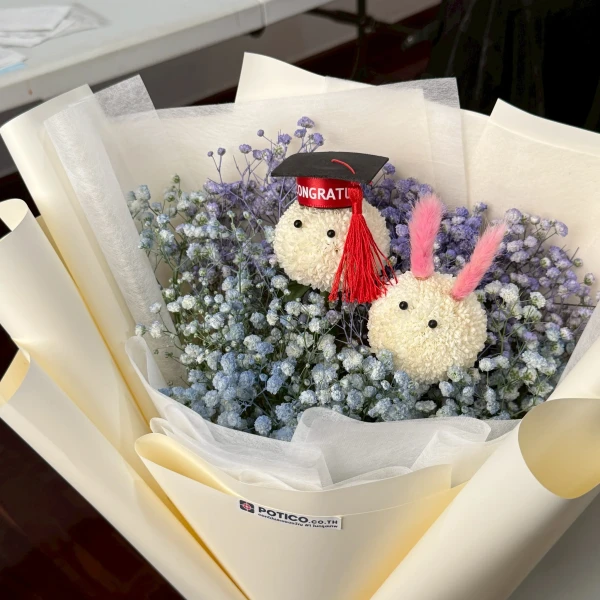 Graduation bouquet with two fluffy bunny-like ornaments and baby's breath flowers.