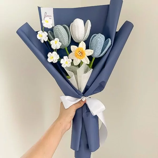 Crocheted daffodil and tulip bouquet wrapped in navy paper with a white ribbon.
