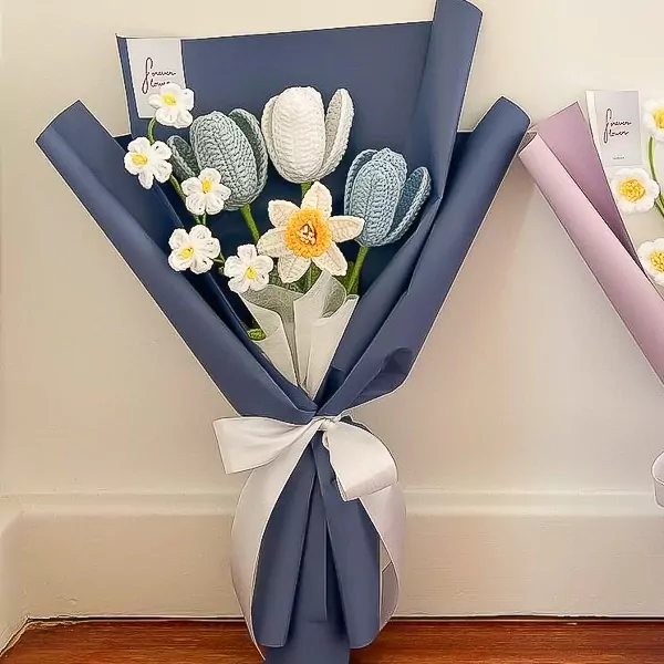 Crocheted daffodil bouquet with blue and white tulips, wrapped in navy paper and tied with a white ribbon.