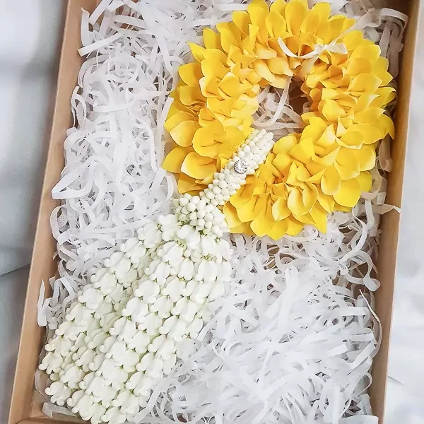Yellow and white flower garland with a diamond accent, presented in a gift box lined with shredded paper.