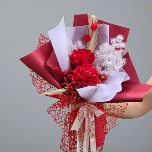 A bouquet of red dried roses and intricate red netting.