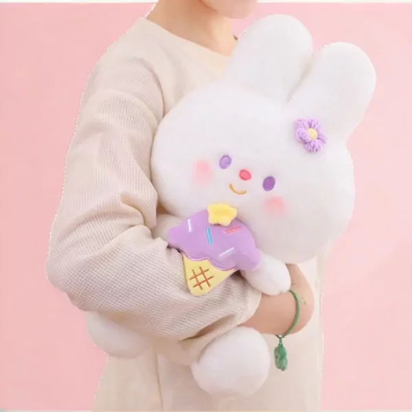 A white plush rabbit with purple flower and ice cream accessory, held by a person in a cream sweater.
