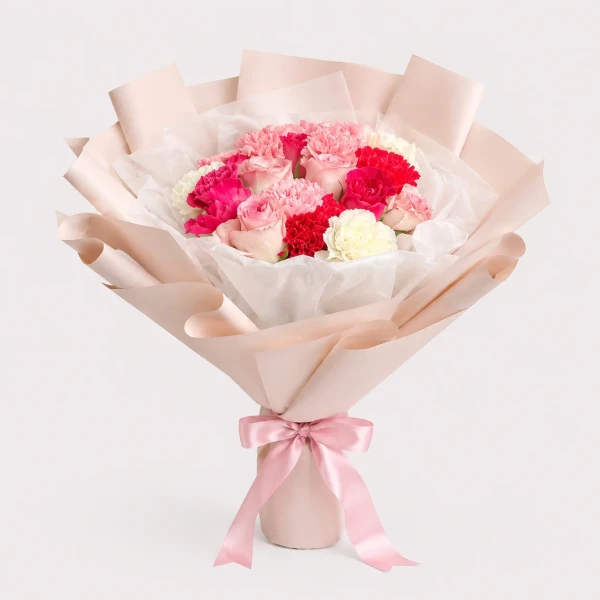 A romantic bouquet of pink, red, and white roses and carnations wrapped in white paper and tied with a pink ribbon.
