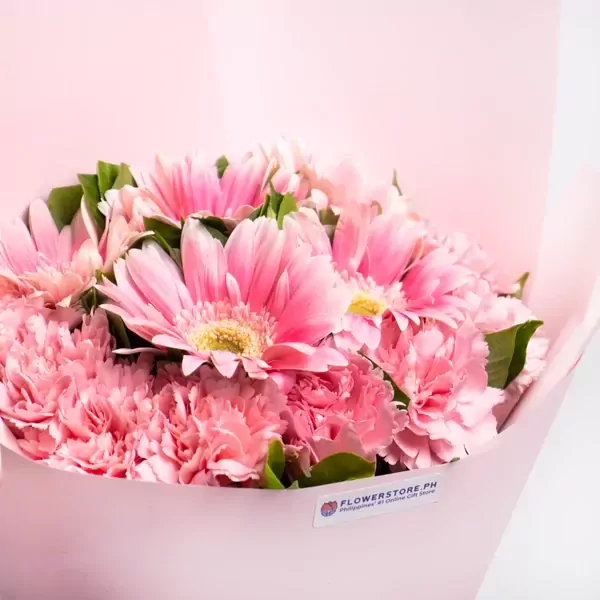 Pink gerbera daisies and carnations in a light pink bouquet with a "flowerstore.ph" sticker.
