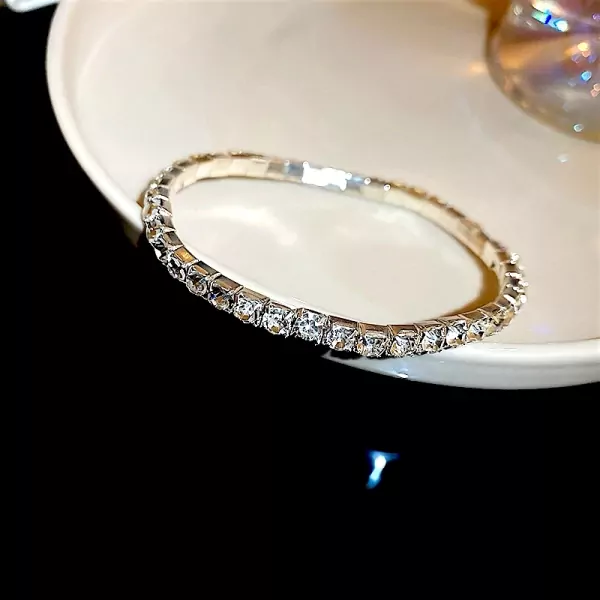 Close-up of a silver tennis bracelet with clear, square-cut stones on a white dish.