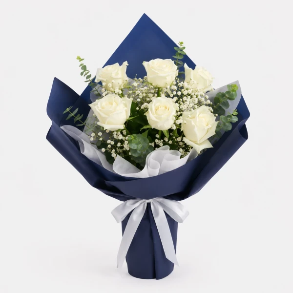 White roses, gypsophila, and eucalyptus in navy blue wrapping paper, tied with a white ribbon.