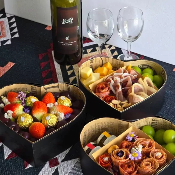 Heart-shaped box with charcuterie, cheese, grapes, strawberries, and chocolates.