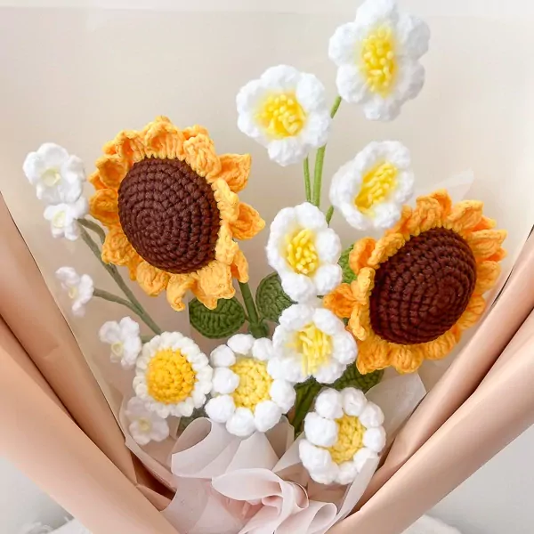Crocheted sunflower bouquet with white flowers, green leaves, and pink wrapping.