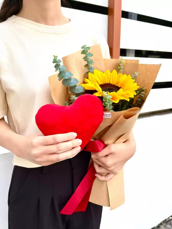 Red heart plush and sunflower bouquet, wrapped in brown paper and tied with red ribbon.