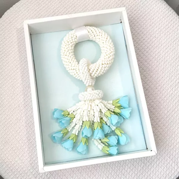 Handmade white jasmine malai garland with light blue flowers in a gift box.