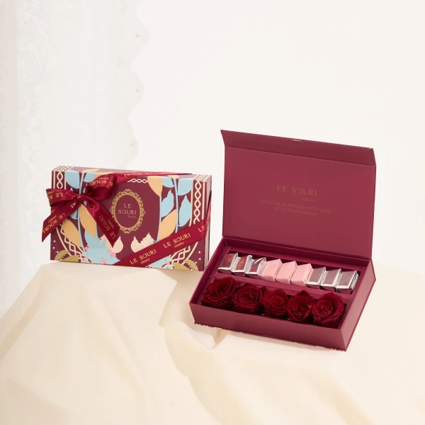 Red box of preserved roses and chocolates, with another decorative box beside it.