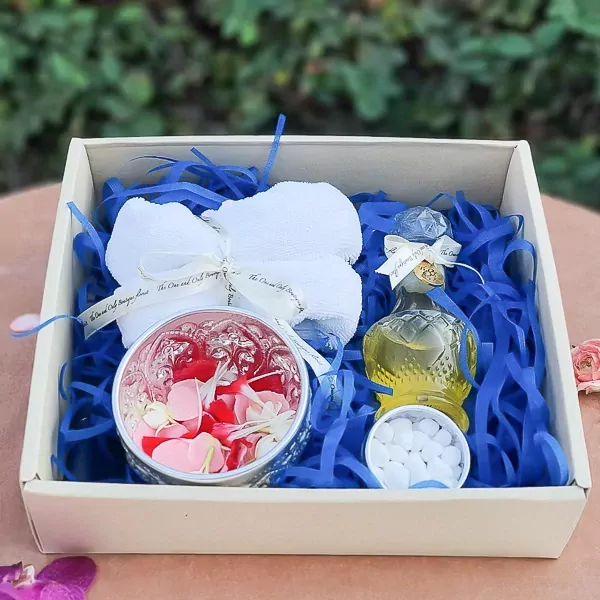 Thai Water Ceremony Set S: A gift box with a white towel, a bowl of flower petals, essence water in a decorative bottle, and white candies.