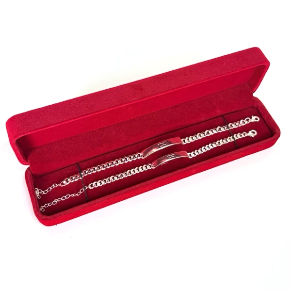 Two silver chain bracelets with infinity symbols in a red velvet box.