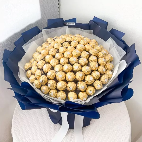 A large bouquet of 100 Ferrero Rocher chocolates, wrapped in dark blue paper with white ribbons.