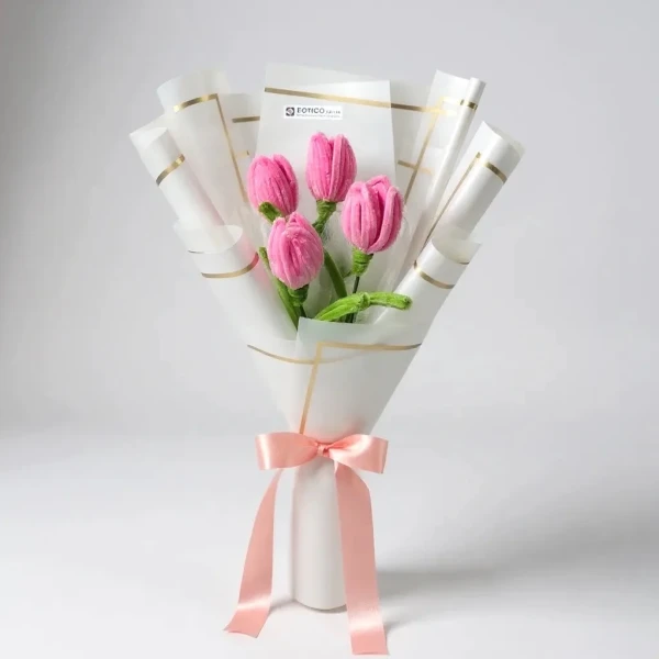 Pink velvet tulips in a white bouquet wrap, tied with a pink ribbon.