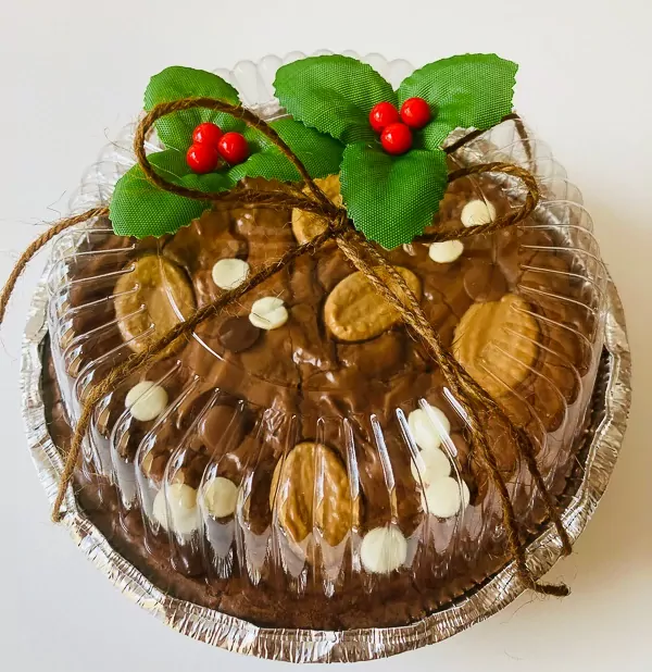 Chocolate brownie with white and dark chocolate chips, topped with holly and berries, tied with twine.