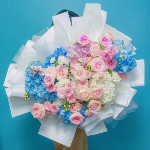 An grand fresh bouquet featuring a dreamy blend of serene blue hydrangeas and pastel pink roses.