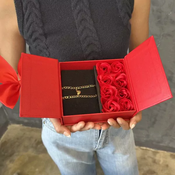 A red gift box holds two magnetic half-heart bracelets and red roses.
