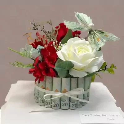 Money cake with red and white roses, folded Thai banknotes, and paper butterfly decoration.