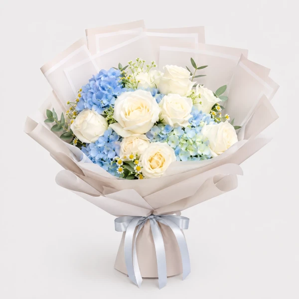 A bouquet of white roses, blue hydrangeas, and daisies wrapped in grey paper with a "Thank You" tag.