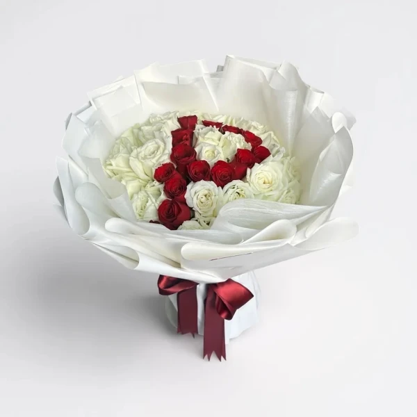 Bouquet of white and red roses arranged to form the initial "P," wrapped in white paper and tied with a red ribbon.