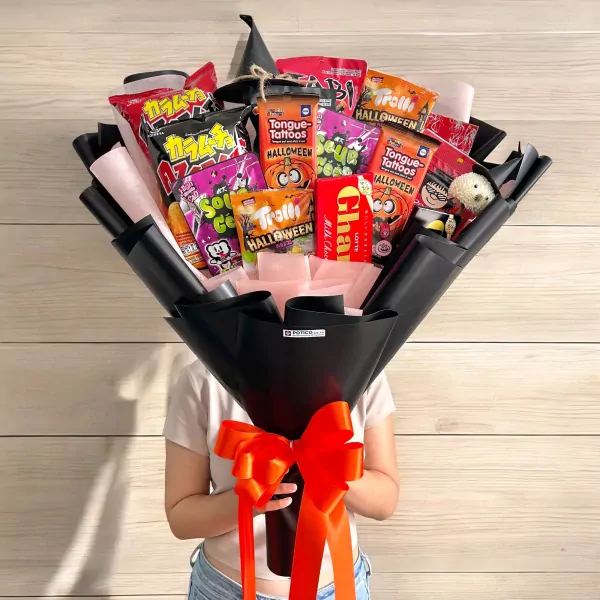 Halloween snack bouquet with assorted candies and treats, wrapped in black paper with an orange ribbon.