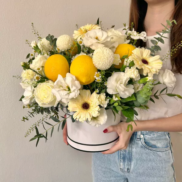 White floral arrangement with lemons in a white hatbox.