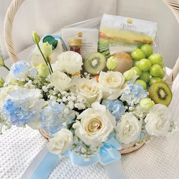 Get well soon basket with white roses, blue hydrangeas, kiwi, grapes, and Doikham products.