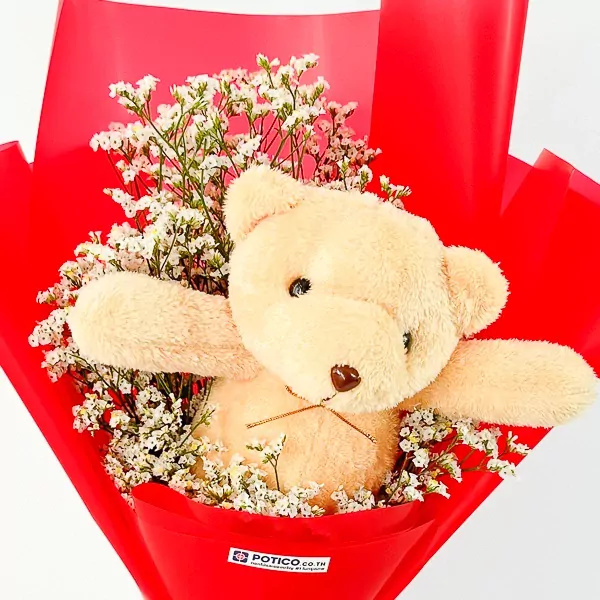 Teddy bear peeking from a bouquet of white flowers in red wrapping.