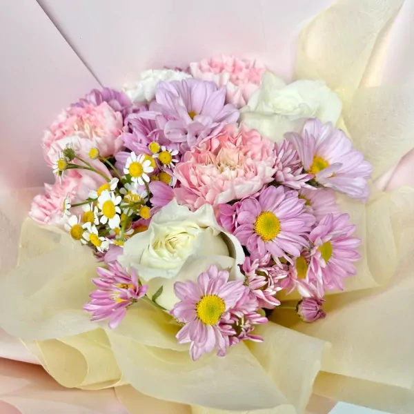 Pink daisy mums, white roses, and chamomile in a blush-toned bouquet.