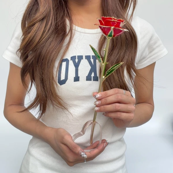 Woman in white t-shirt holds a red 24K gold dipped rose with a heart-shaped stand.