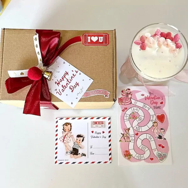Valentine's gift box with candle, board game, and postcard.