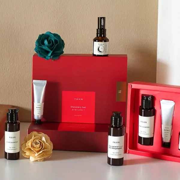Red gift box with skincare bottles, a tube, and a blue decorative flower.
