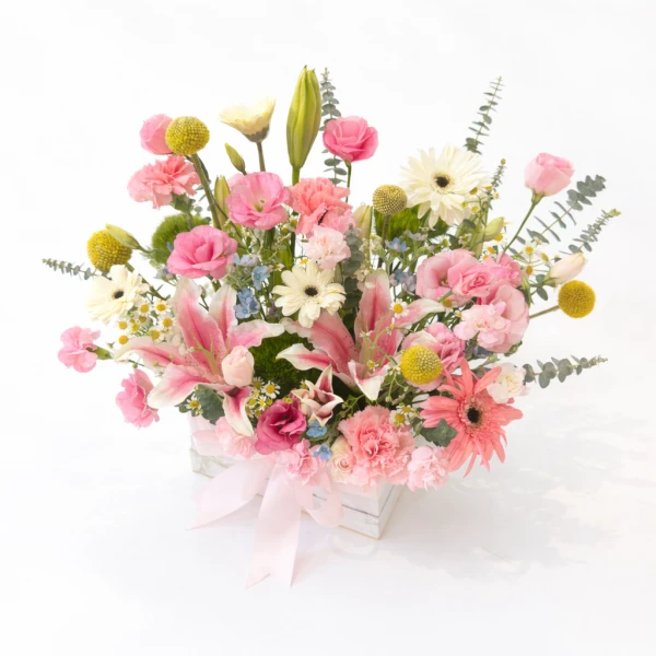 Pink lilies, gerberas, and carnations in a white box with a pink ribbon.