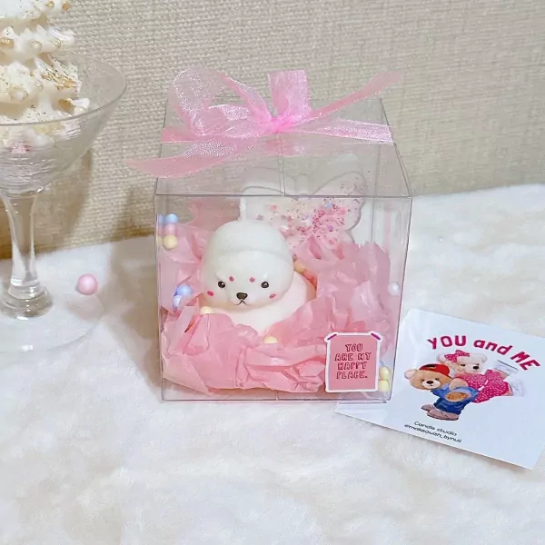 Cute seal-shaped candle in a clear box with pink tissue paper and a pink bow.