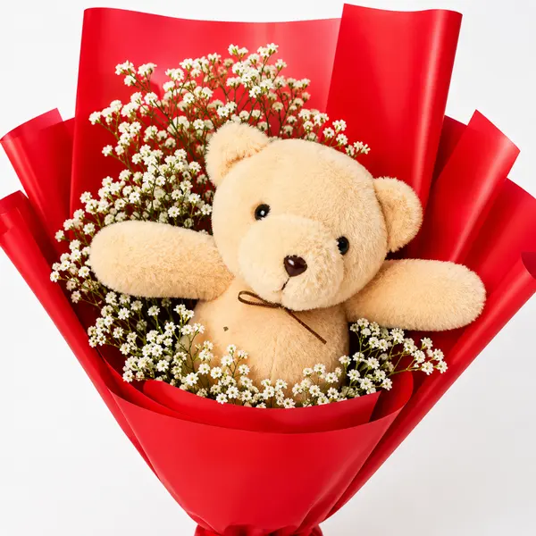 Teddy bear peeking from a bouquet of white flowers in red wrapping.